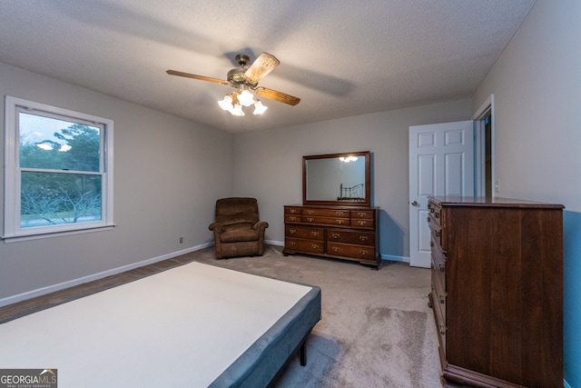 bedroom featuring a textured ceiling, light colored carpet, and ceiling fan