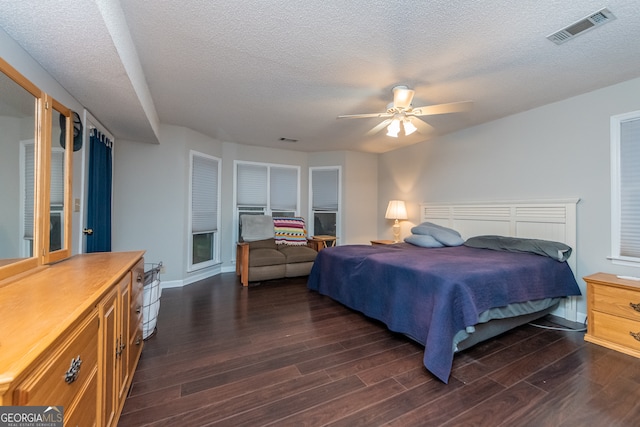 bedroom featuring dark hardwood / wood-style floors, ceiling fan, and a textured ceiling