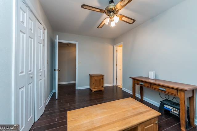 home office with dark hardwood / wood-style flooring and ceiling fan