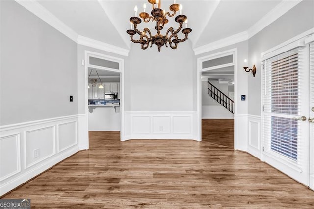 unfurnished dining area with crown molding, hardwood / wood-style floors, an inviting chandelier, and vaulted ceiling