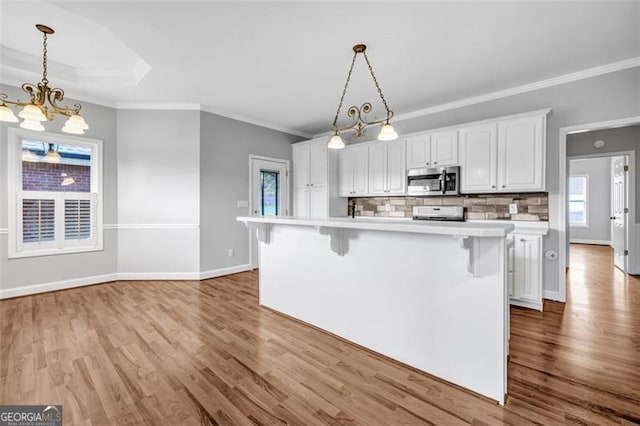 kitchen with a center island, tasteful backsplash, white cabinets, pendant lighting, and a breakfast bar