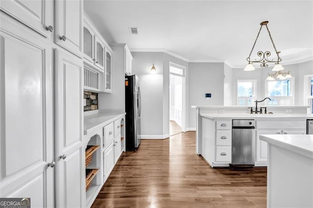 kitchen with white cabinets, decorative light fixtures, sink, stainless steel fridge, and crown molding