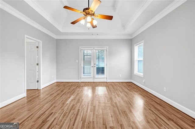 unfurnished room featuring hardwood / wood-style floors, a tray ceiling, ornamental molding, and a healthy amount of sunlight