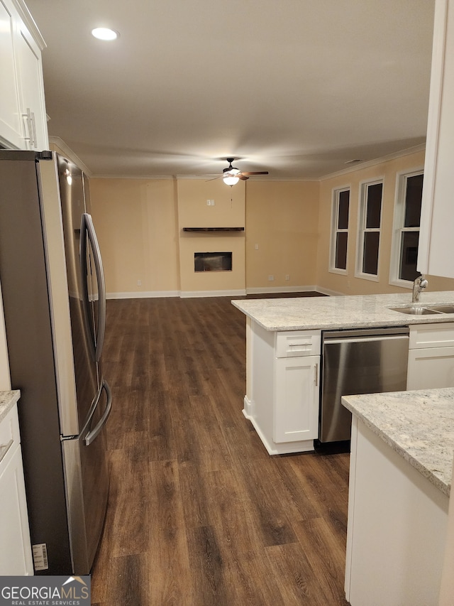 kitchen with light stone countertops, sink, stainless steel appliances, dark hardwood / wood-style floors, and white cabinets