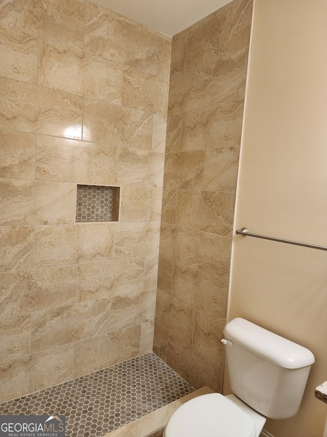 bathroom with tiled shower and toilet