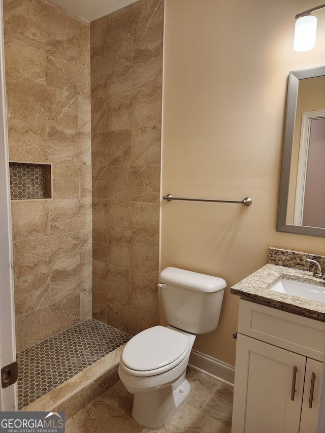 bathroom with tiled shower, vanity, and toilet