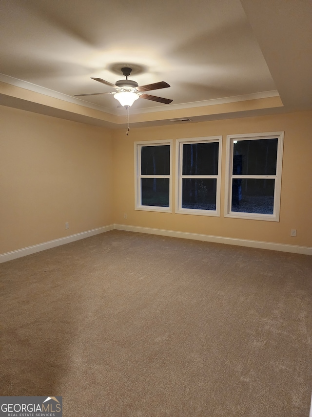 carpeted spare room featuring a tray ceiling, ceiling fan, and crown molding