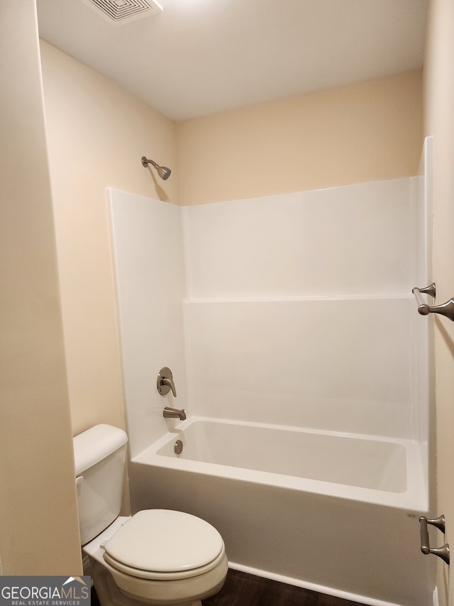 bathroom featuring washtub / shower combination, wood-type flooring, and toilet