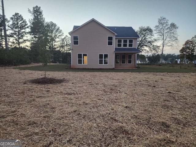 back house at dusk with a lawn