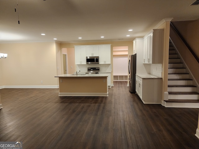 kitchen with a kitchen island with sink, white cabinets, dark hardwood / wood-style floors, decorative backsplash, and stainless steel appliances