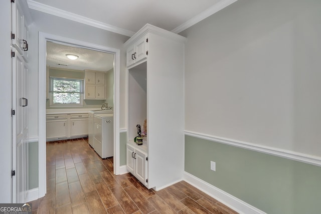 laundry room with sink, crown molding, washing machine and dryer, dark hardwood / wood-style floors, and cabinets