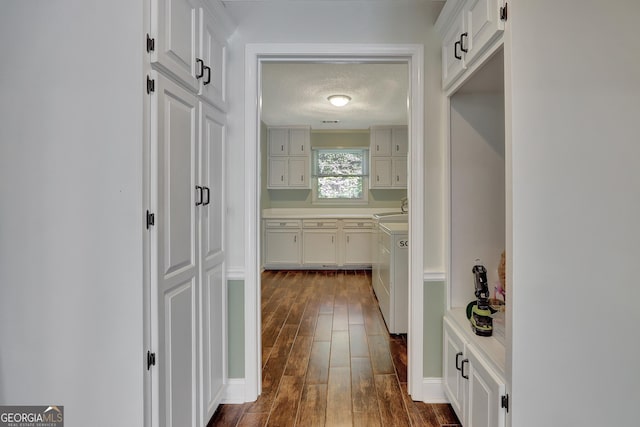 hall with sink, dark wood-type flooring, washer and clothes dryer, and a textured ceiling