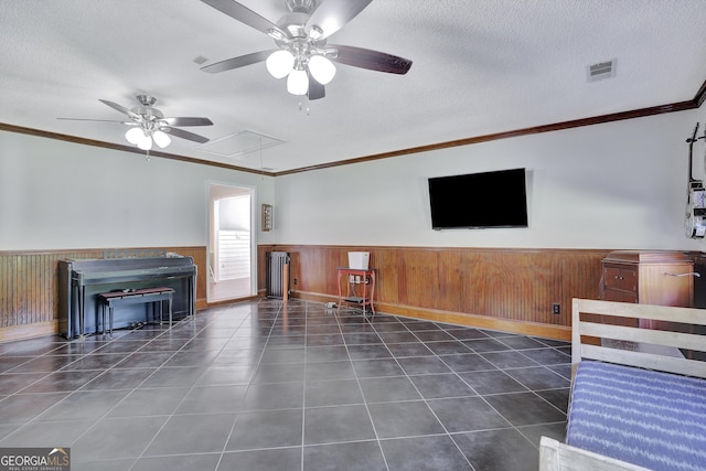 unfurnished living room with dark tile patterned floors, wooden walls, ornamental molding, and a textured ceiling