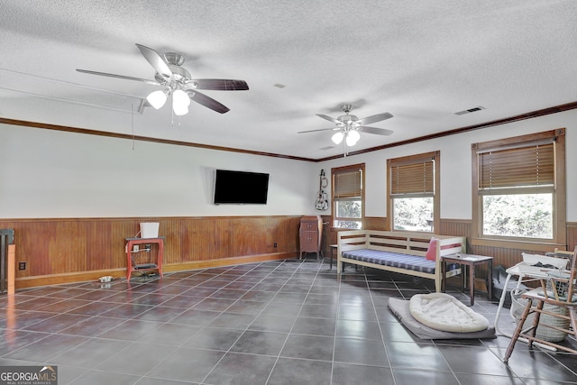 sitting room with ceiling fan, ornamental molding, dark tile patterned flooring, and a textured ceiling