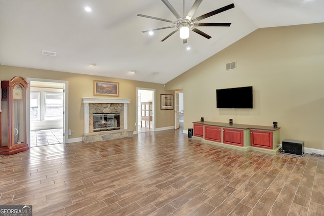 living room with hardwood / wood-style flooring, ceiling fan, high vaulted ceiling, and a fireplace