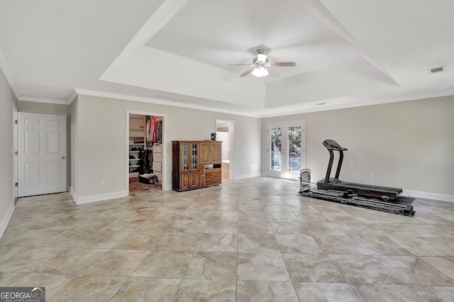 workout area with french doors, ceiling fan, a textured ceiling, and a tray ceiling