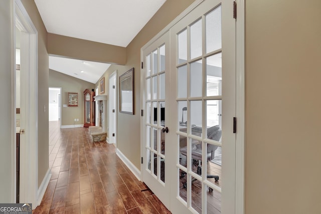 corridor with vaulted ceiling, dark hardwood / wood-style floors, and french doors