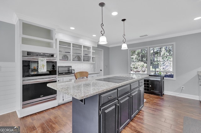 kitchen with a breakfast bar, decorative light fixtures, a kitchen island, light stone countertops, and black appliances