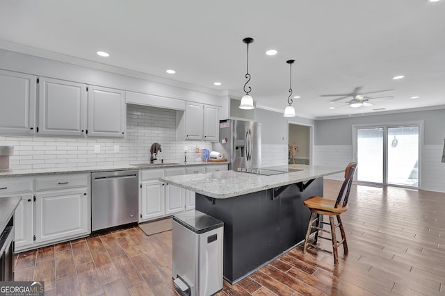 kitchen with sink, a breakfast bar area, white cabinetry, stainless steel appliances, and a kitchen island