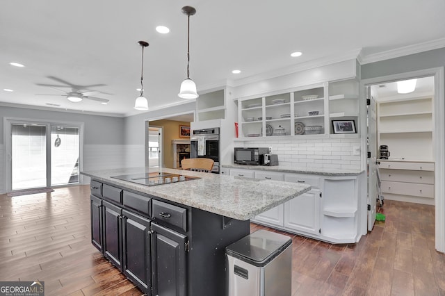 kitchen with decorative light fixtures, white cabinets, a center island, light stone counters, and black appliances