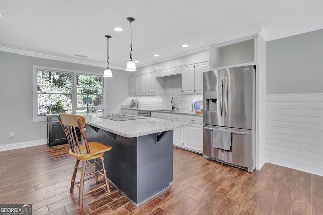 kitchen featuring sink, a kitchen bar, light stone countertops, a kitchen island, and stainless steel fridge with ice dispenser