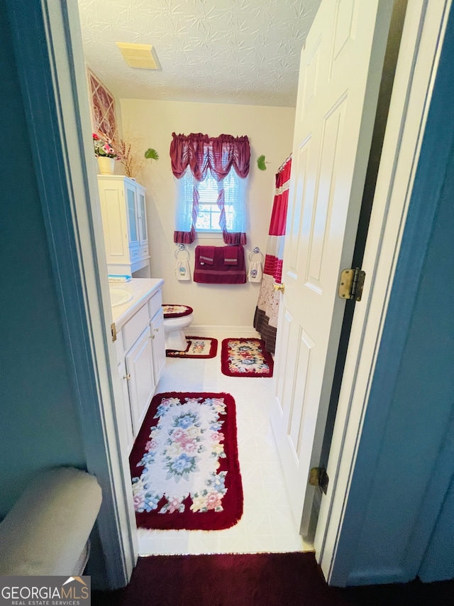 bathroom featuring vanity, a textured ceiling, and toilet