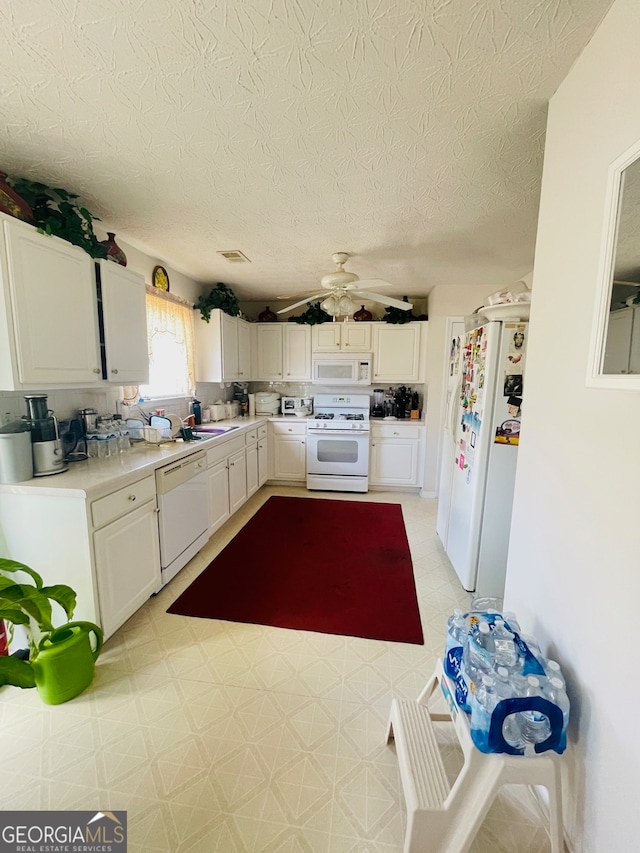 kitchen featuring white appliances, sink, a textured ceiling, ceiling fan, and white cabinets