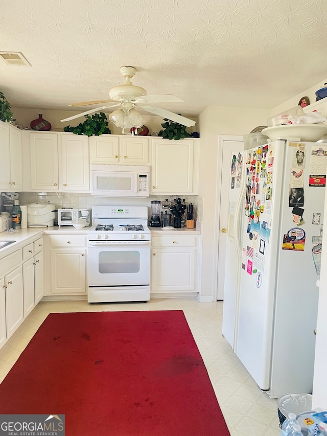 kitchen with white appliances, backsplash, white cabinetry, and ceiling fan