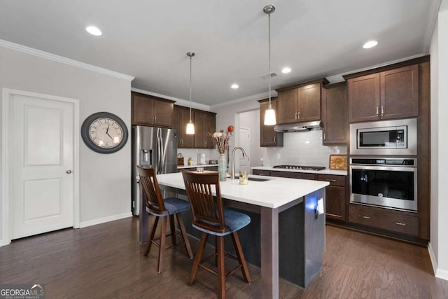 kitchen featuring dark hardwood / wood-style floors, an island with sink, stainless steel appliances, sink, and decorative light fixtures