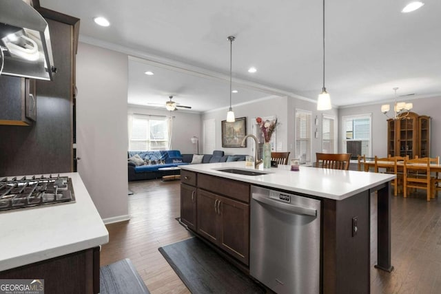 kitchen featuring dark wood-type flooring, hanging light fixtures, a center island with sink, sink, and appliances with stainless steel finishes