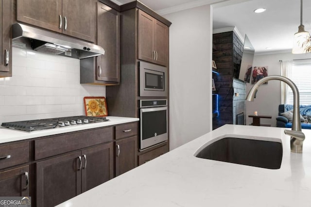 kitchen with tasteful backsplash, hanging light fixtures, sink, dark brown cabinetry, and stainless steel appliances