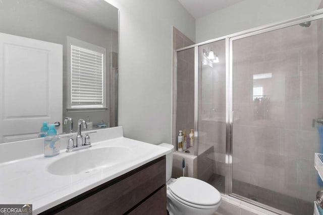 bathroom with toilet, vanity, and a shower with door