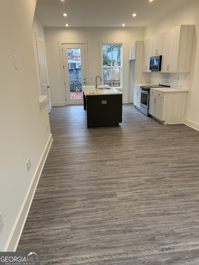 kitchen featuring backsplash, dark hardwood / wood-style floors, sink, a kitchen island with sink, and stainless steel range with electric cooktop