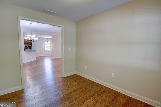 empty room with a notable chandelier and hardwood / wood-style floors