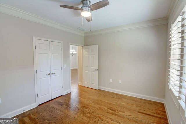 unfurnished bedroom with a closet, ceiling fan, hardwood / wood-style flooring, and crown molding