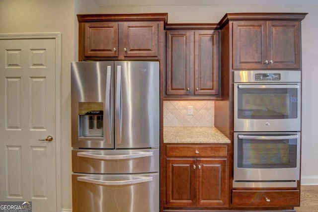 kitchen with decorative backsplash, stainless steel appliances, and light stone counters