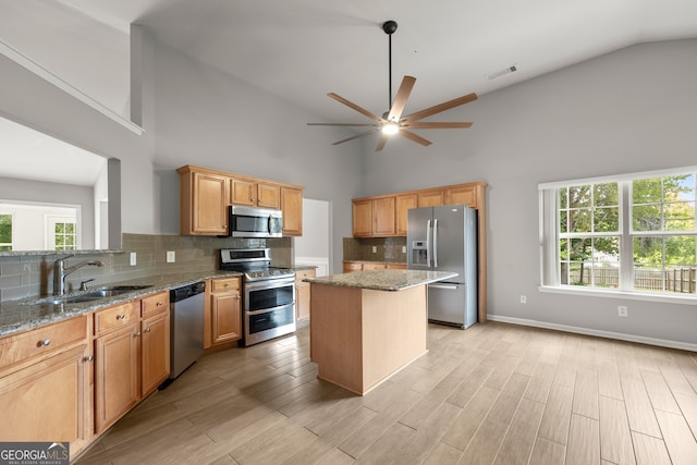 kitchen featuring light stone countertops, sink, appliances with stainless steel finishes, and a kitchen island