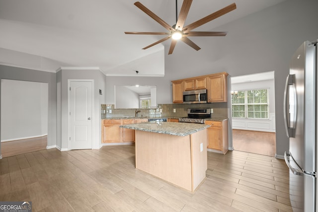 kitchen with a kitchen island, appliances with stainless steel finishes, vaulted ceiling, light hardwood / wood-style flooring, and light stone counters