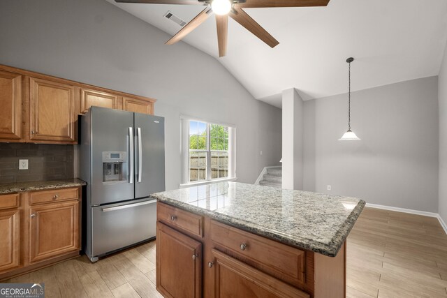 kitchen featuring decorative backsplash, ceiling fan, stainless steel fridge with ice dispenser, light hardwood / wood-style flooring, and a center island