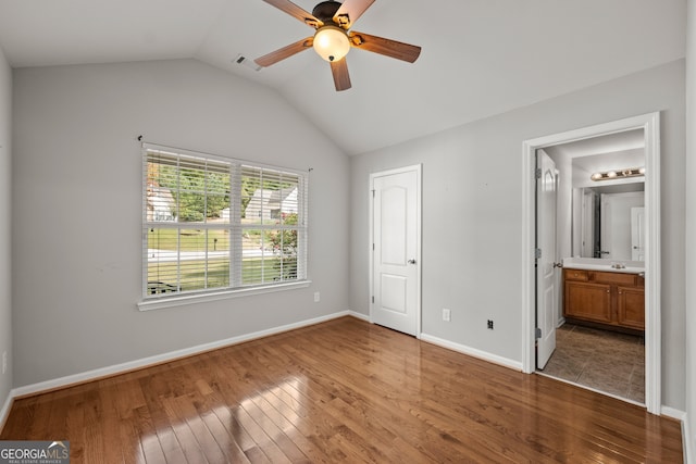 unfurnished bedroom with connected bathroom, ceiling fan, lofted ceiling, and hardwood / wood-style floors