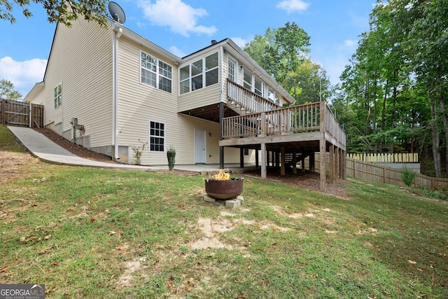 rear view of property featuring a wooden deck and a lawn