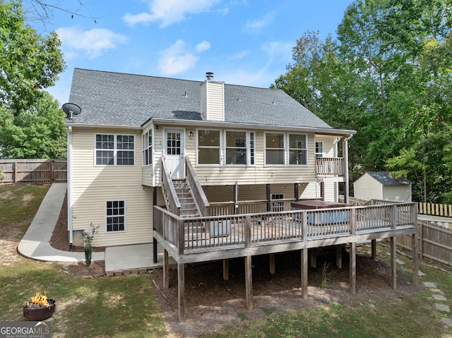 rear view of property with a wooden deck and an outdoor fire pit