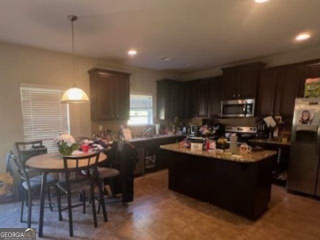 kitchen featuring a kitchen island, appliances with stainless steel finishes, dark brown cabinets, and decorative light fixtures