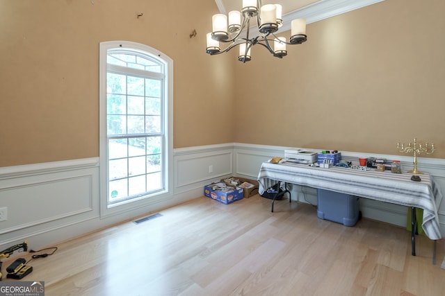 dining room with an inviting chandelier, light hardwood / wood-style flooring, and crown molding