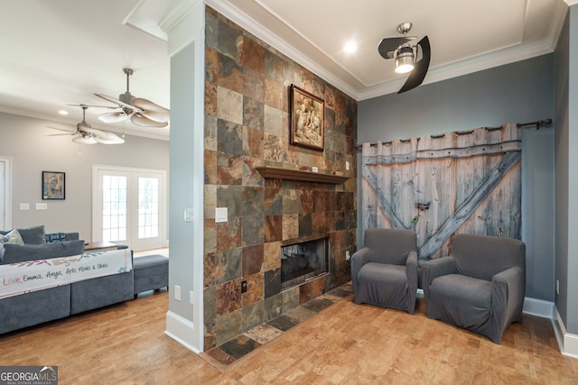 sitting room with ornamental molding, light hardwood / wood-style flooring, a fireplace, and ceiling fan