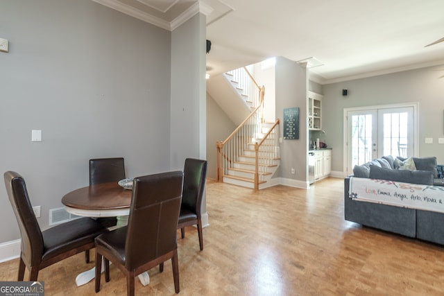 dining area featuring french doors, crown molding, light wood-type flooring, and ceiling fan