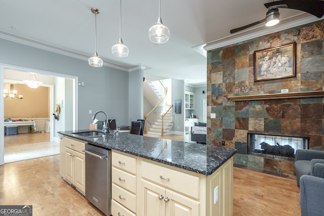 kitchen featuring cream cabinets, hanging light fixtures, dark stone counters, crown molding, and sink