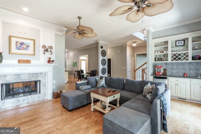 living room with ornamental molding, light hardwood / wood-style floors, and ceiling fan