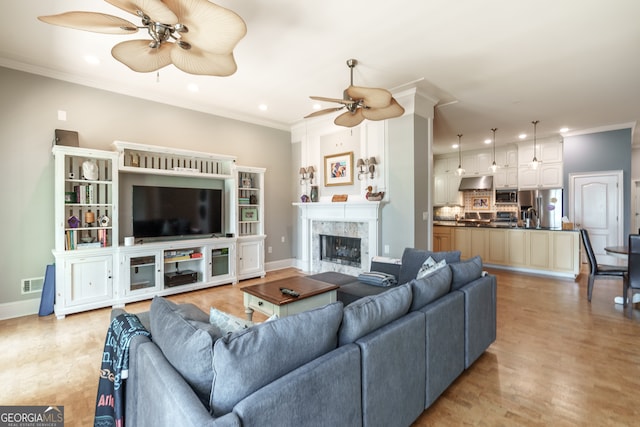 living room featuring crown molding, a fireplace, and ceiling fan