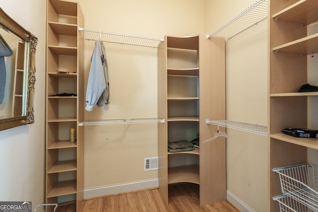 walk in closet with light hardwood / wood-style flooring